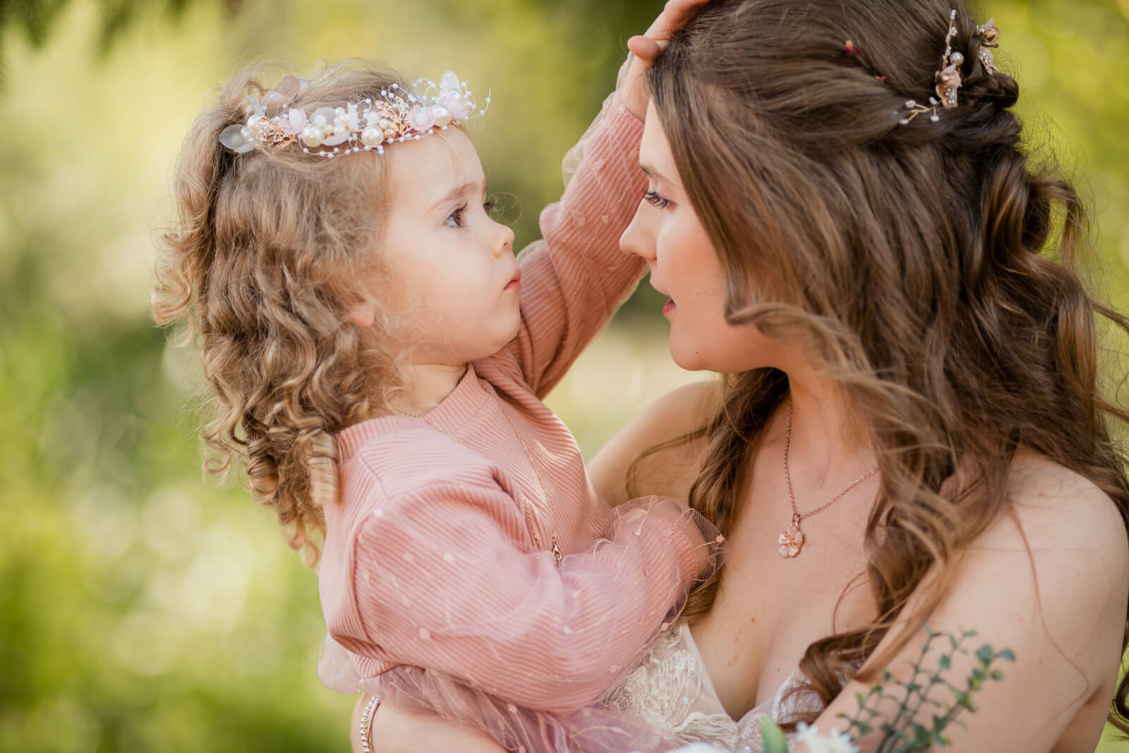 Bride holding flower girl as they share a tender moment outdoors