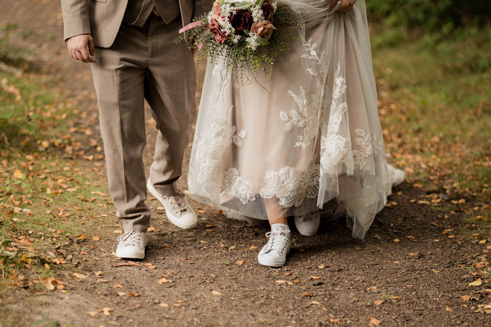Bride and groom walking together showing wedding dress details and bouquet