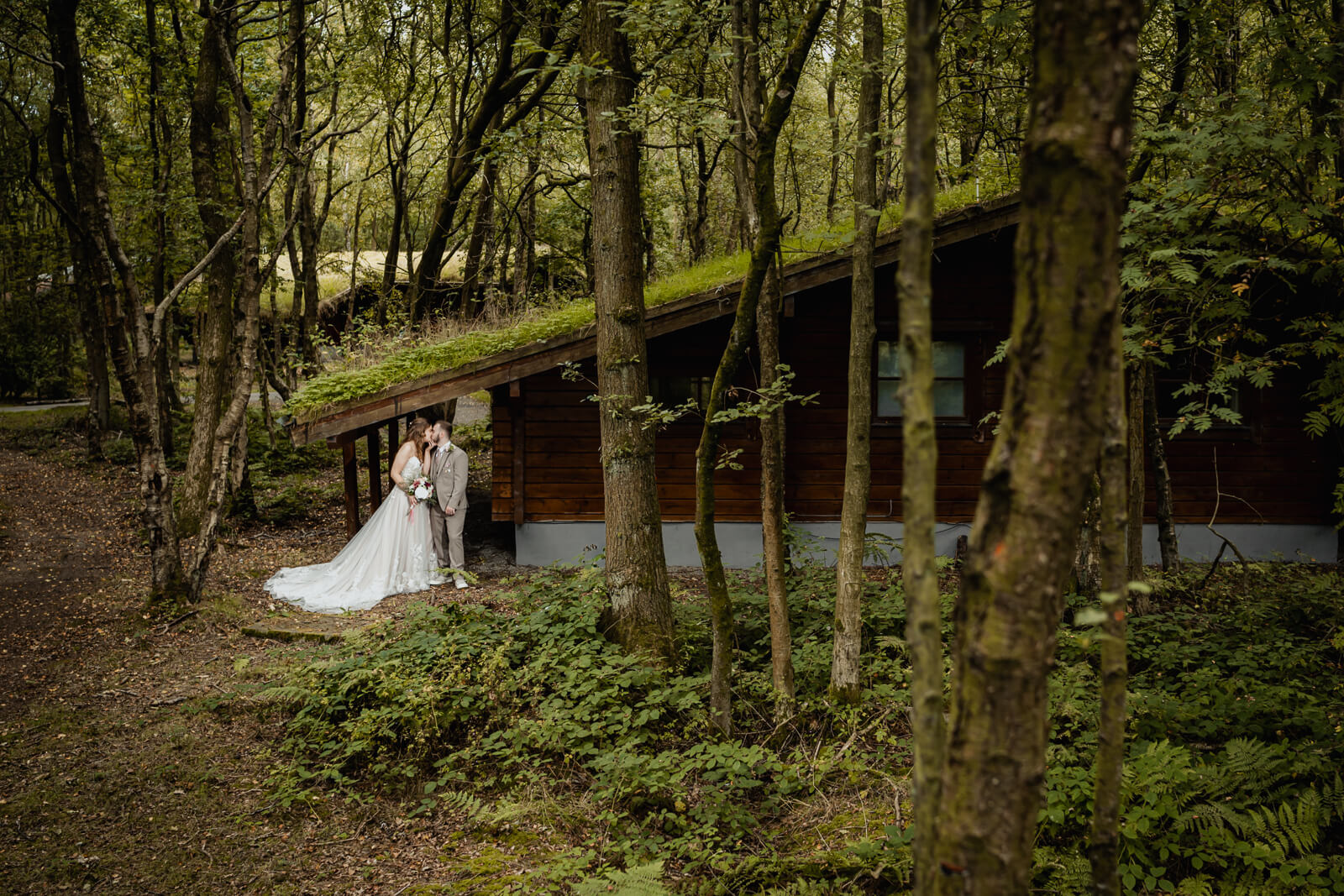 Bride and groom beside woodland cabin at Chevin Country Park wedding venue