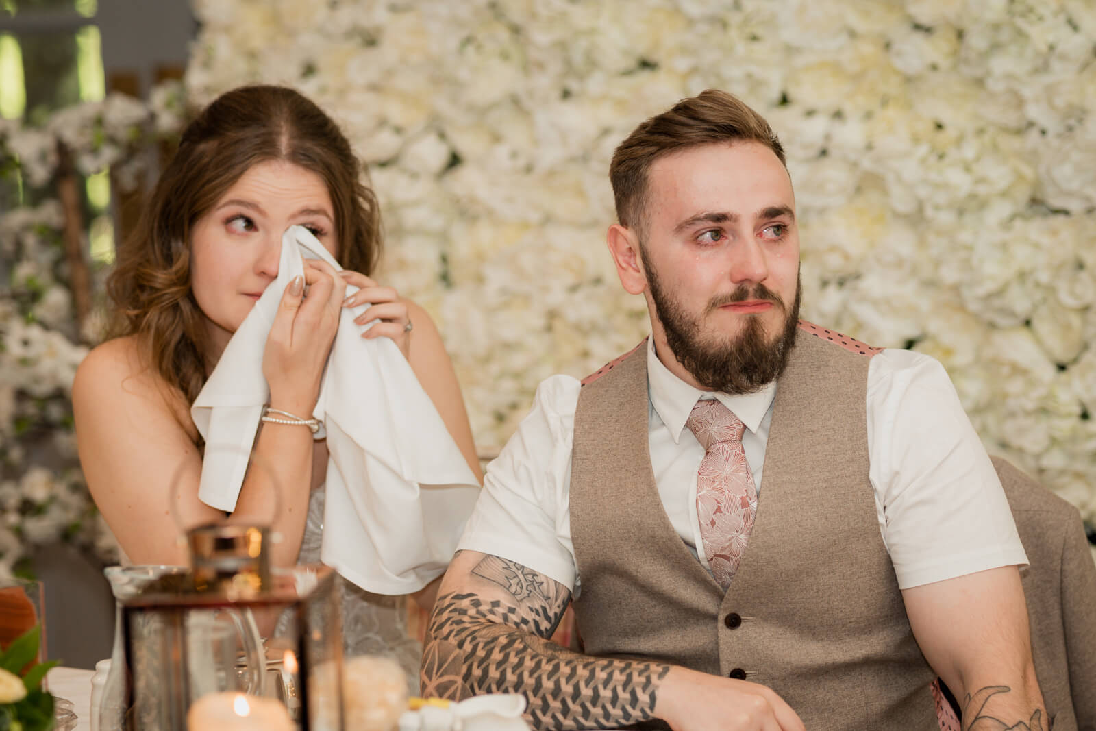 Bride wiping tears beside groom during wedding speech at Chevin Country Park