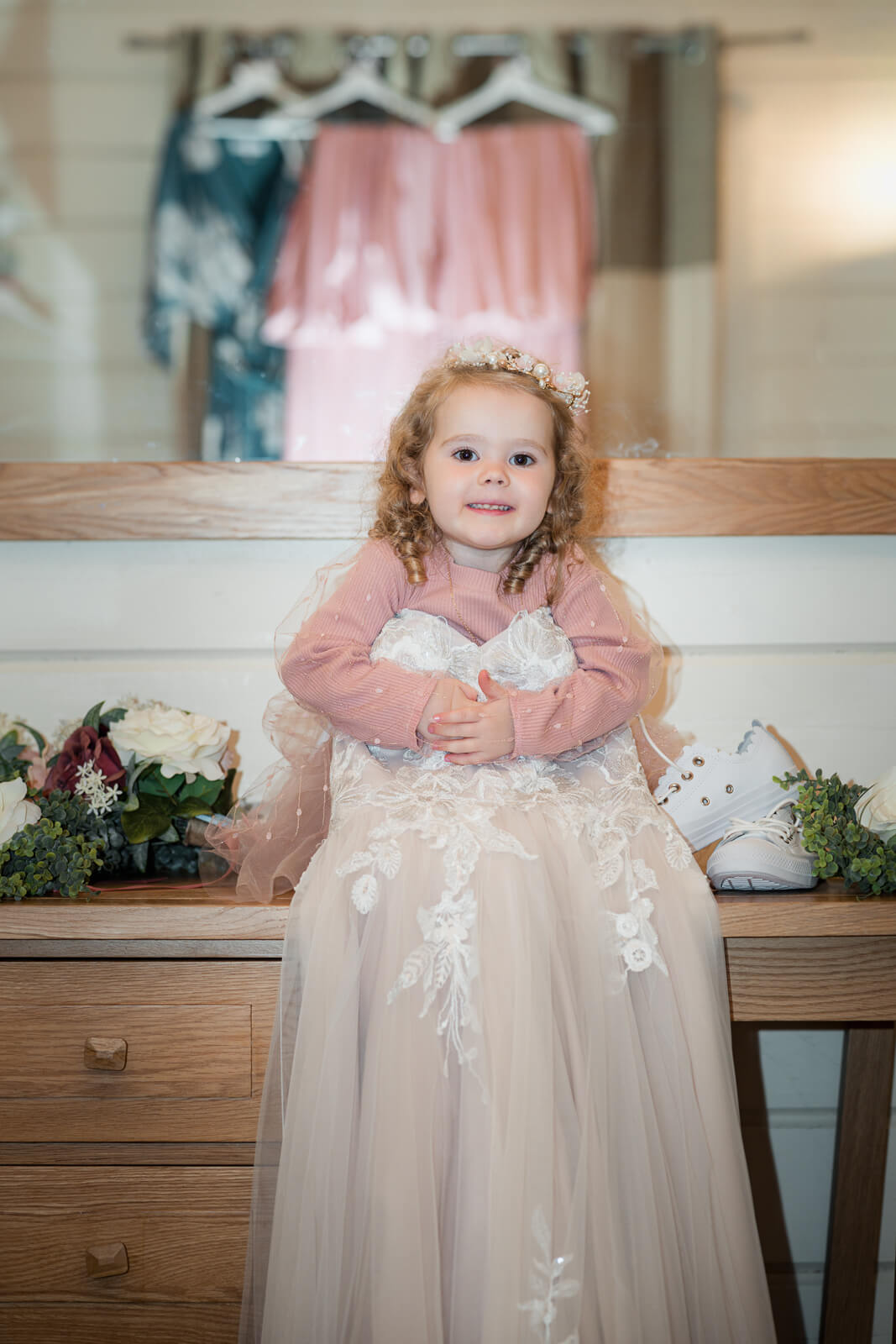 Flower girl in a wedding dress sitting on a table during morning preparations