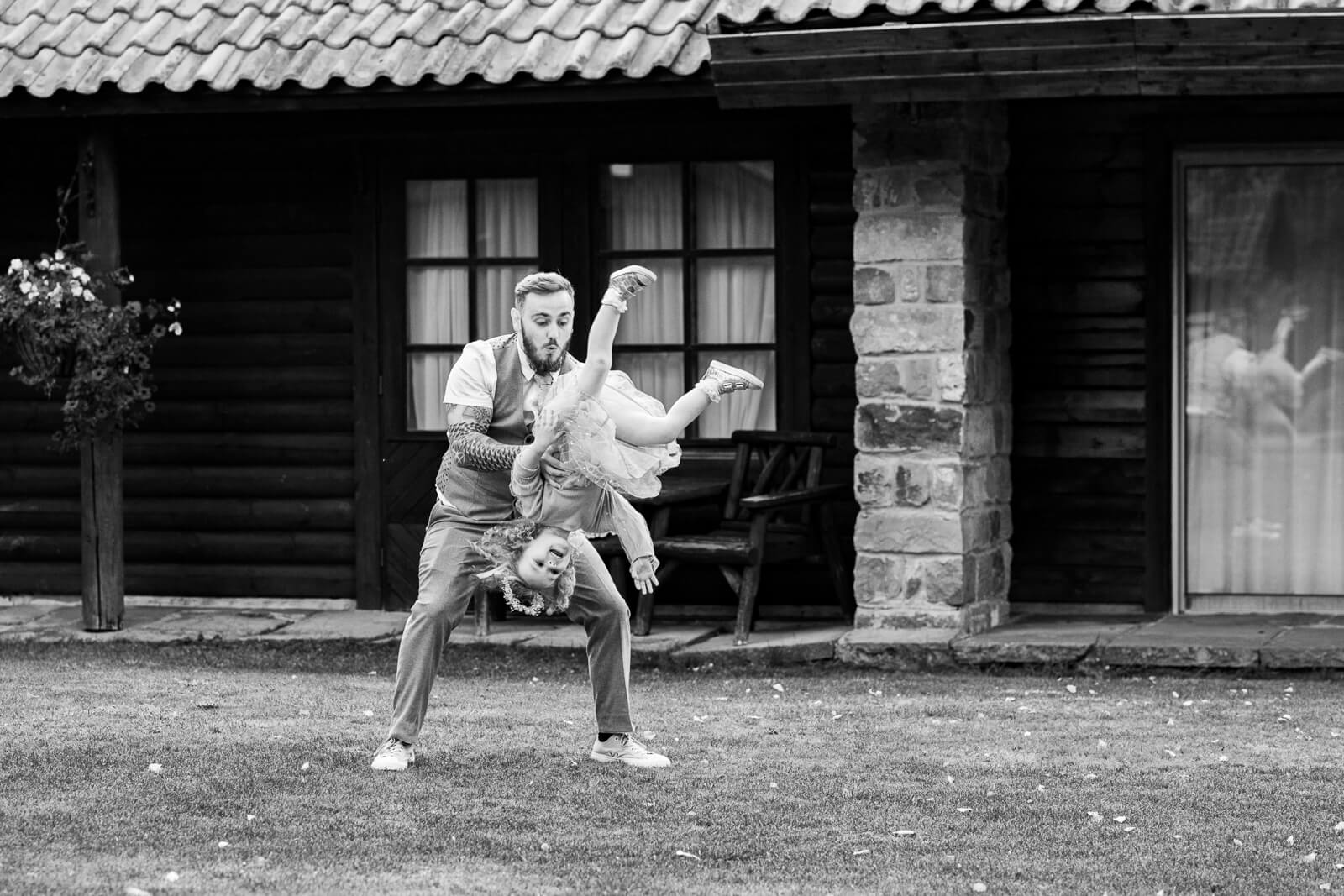 Groom playfully spinning flower girl upside down at Chevin Country Park wedding