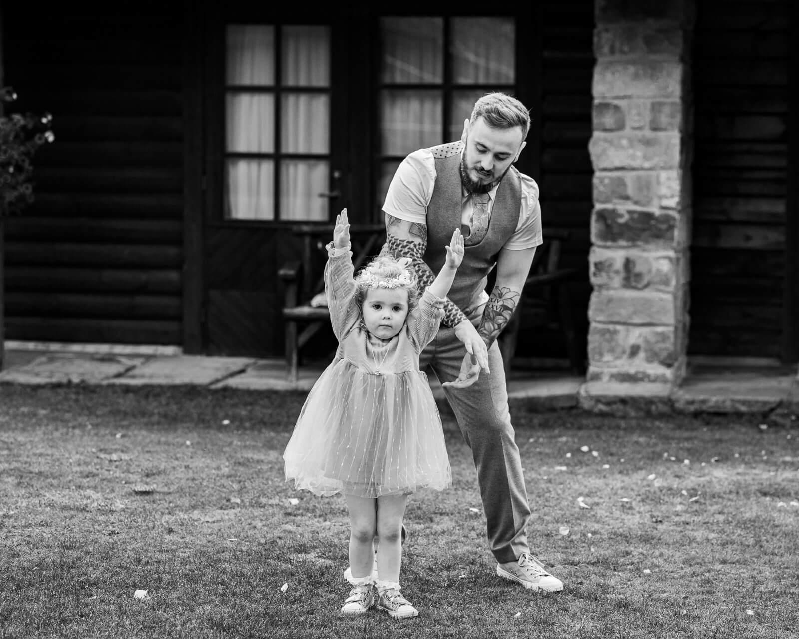 Groom helping flower girl stand during outdoor wedding at Chevin Country Park