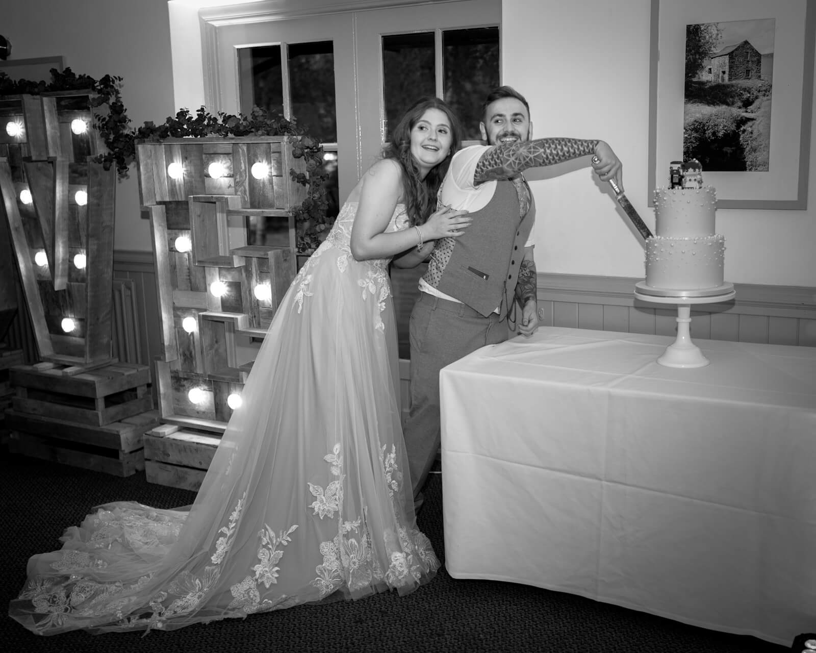 Bride and groom cutting wedding cake at Chevin Country Park reception with LOVE letters