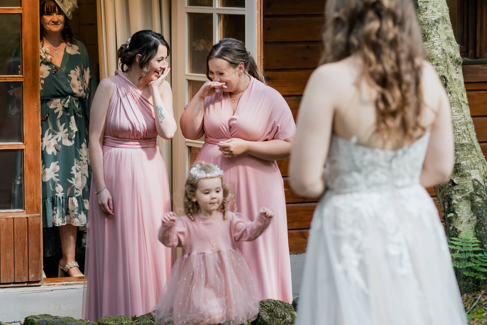 Bridesmaids reacting emotionally as they see the bride outside
