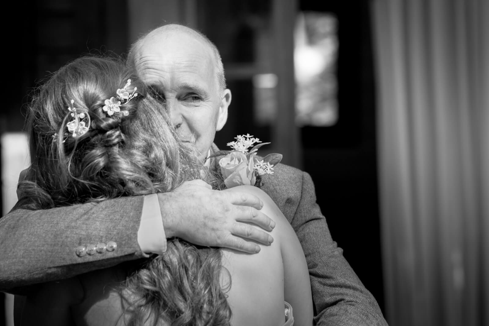 Father hugging bride during emotional wedding moment