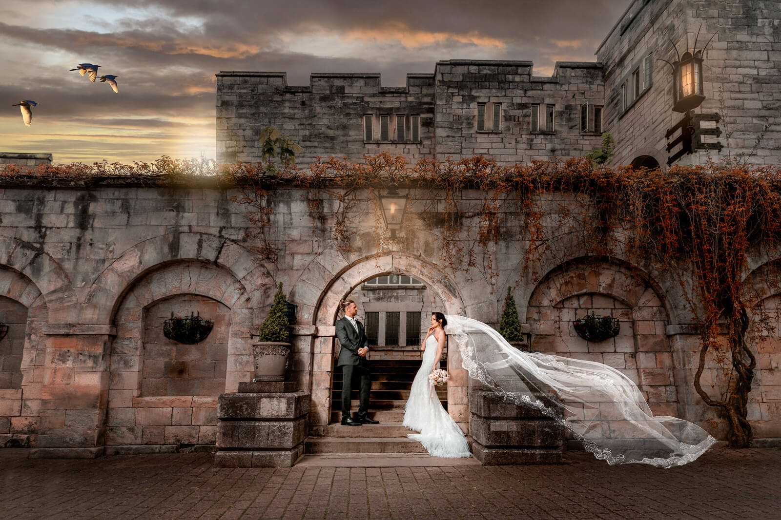 wedding couple framed by historic stone architecture and flowing veil