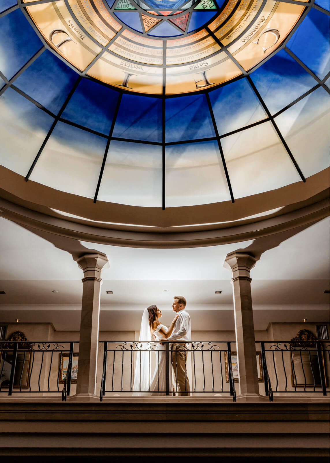 couple standing under a glass dome ceiling with symmetrical composition