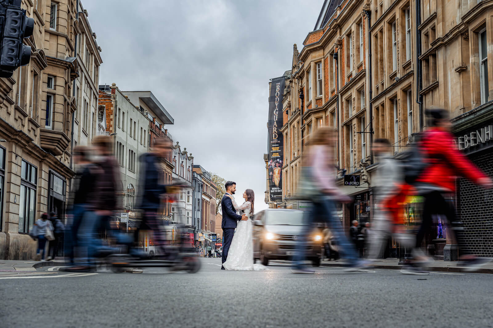 wedding couple standing still while people move around them in the city