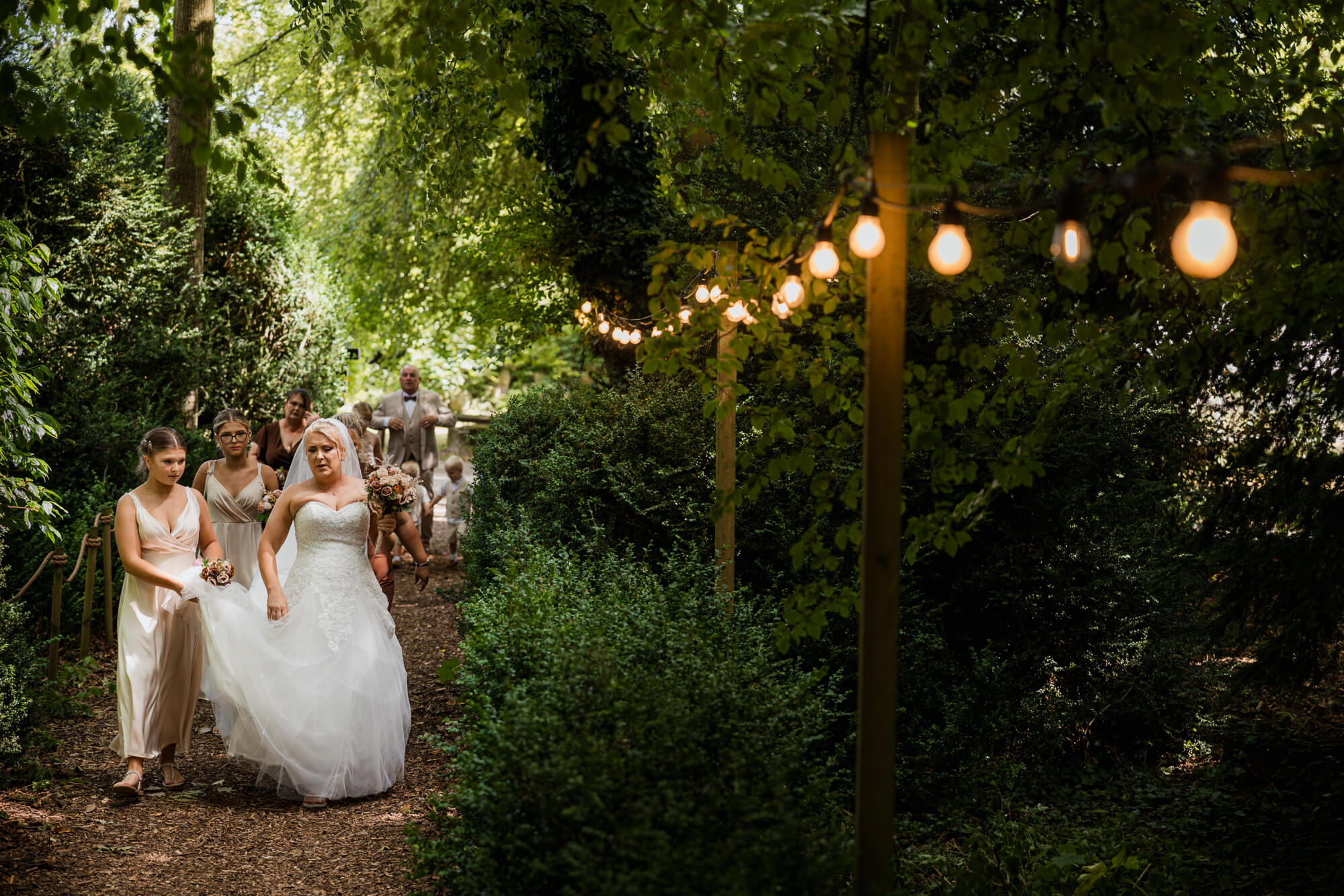 Bride walking through the woodland towards the ceremony at Hazlewood Castle.