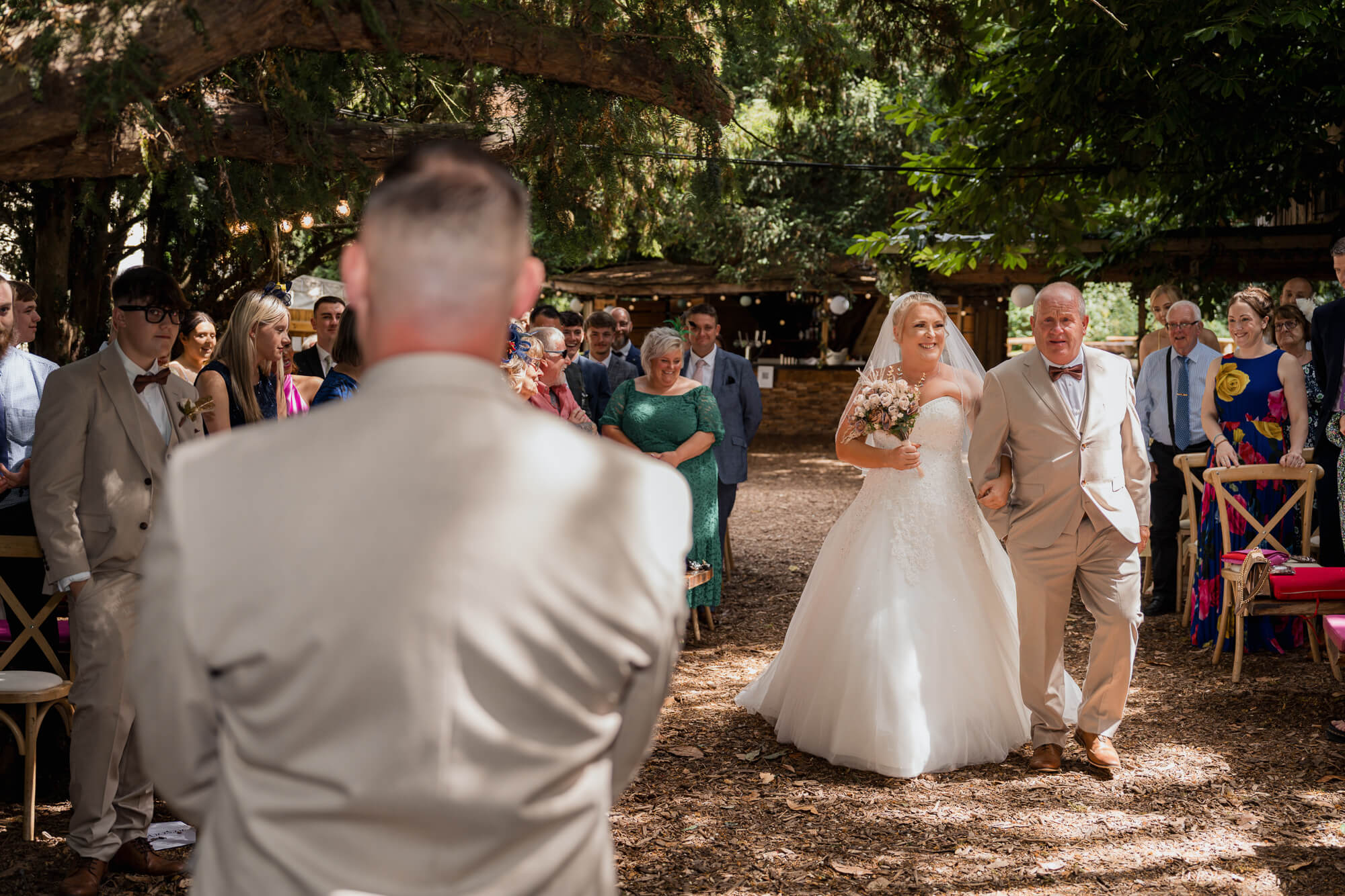 Bride walking down the aisle with her father at Hazlewood Castle woodland wedding.