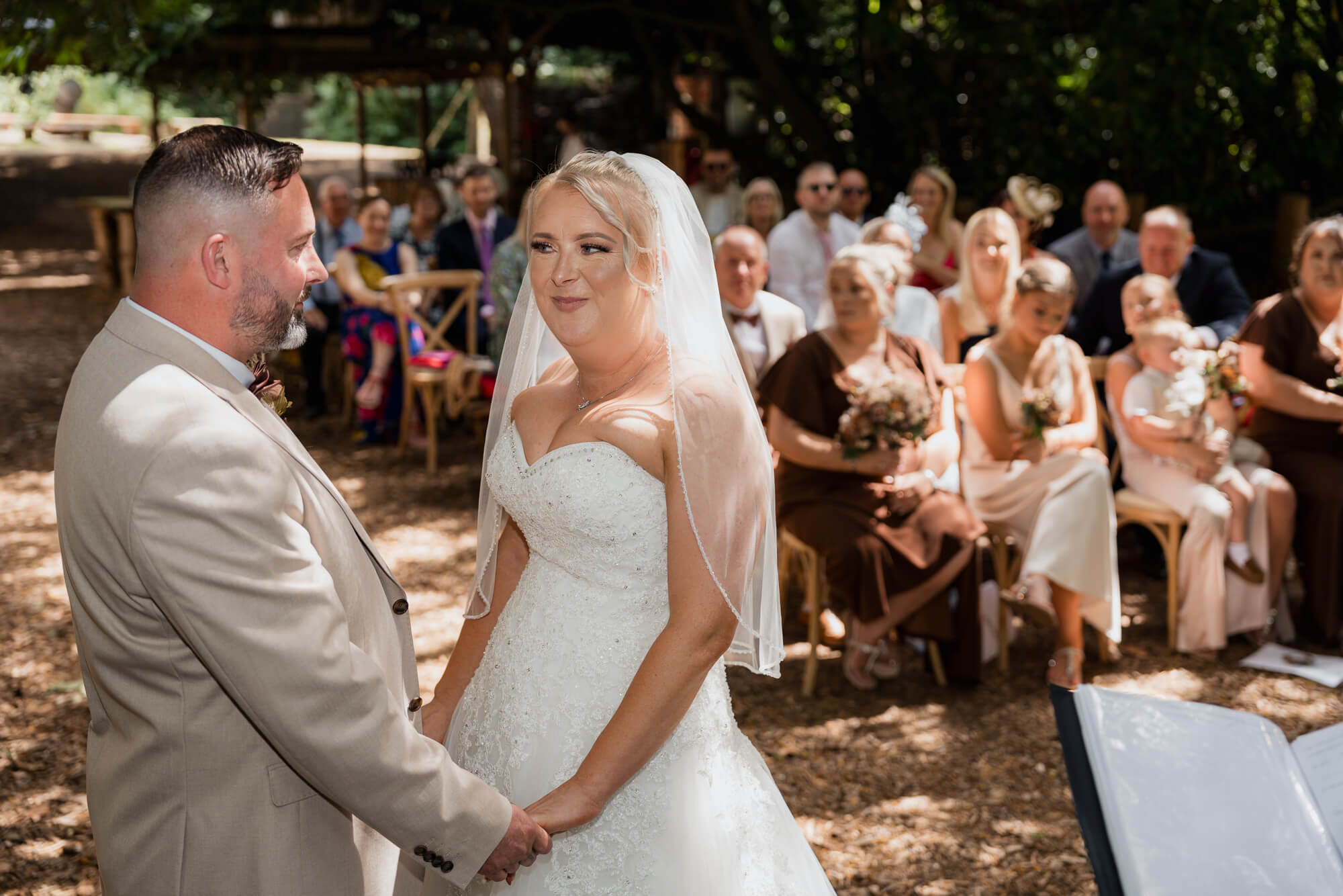Bride and groom holding hands during their woodland wedding ceremony.