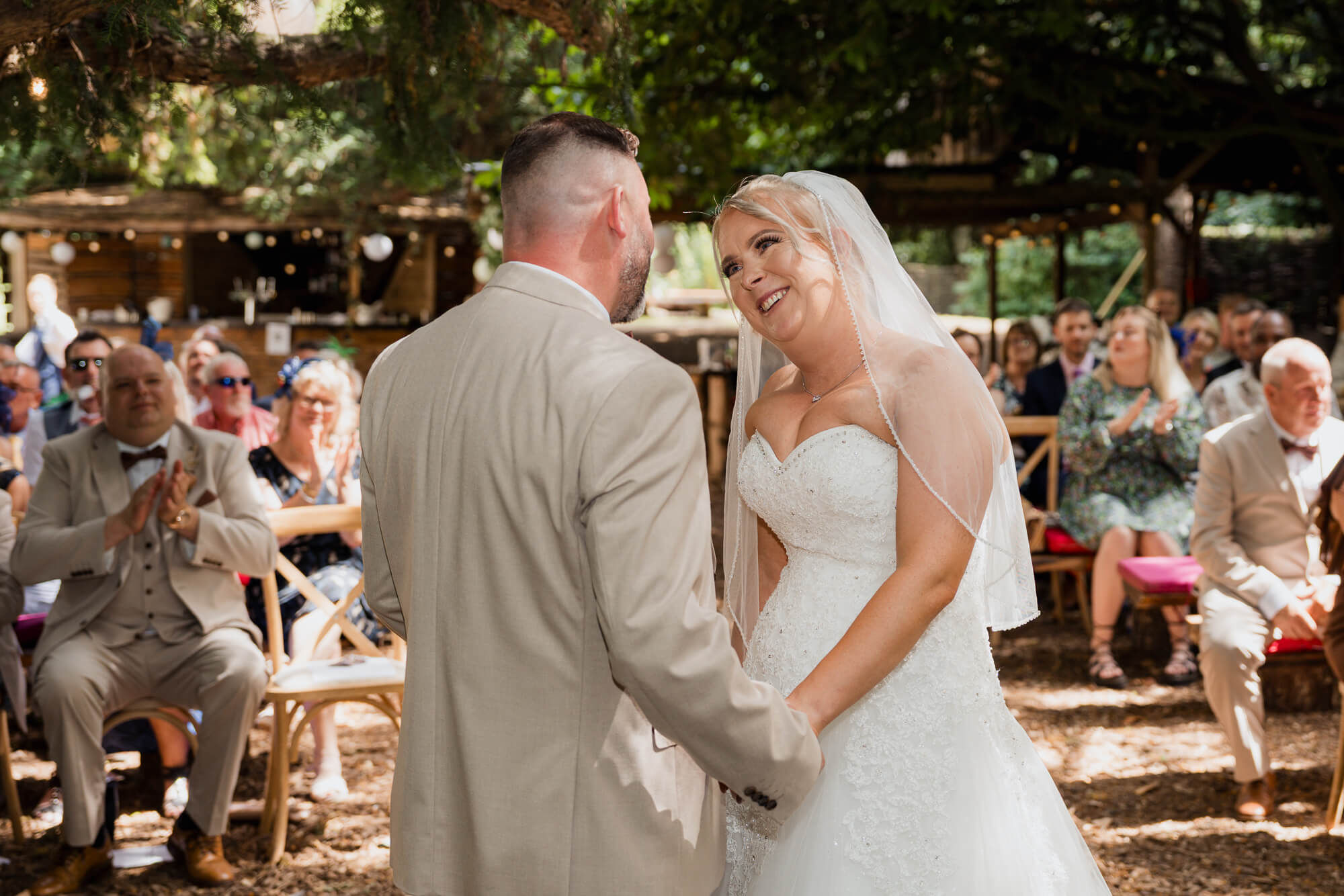 Bride smiling at the groom during the woodland wedding ceremony.