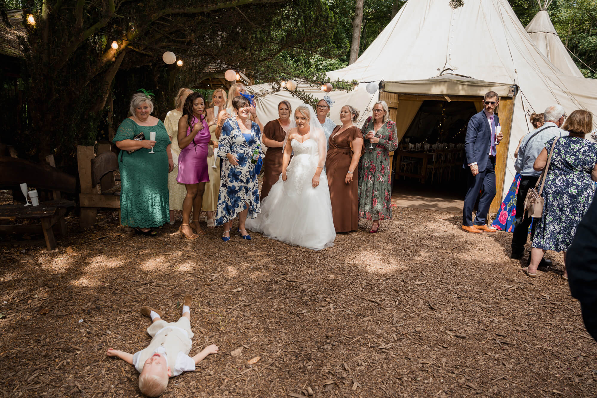 Wedding guests gathering outside the woodland reception tipi at Hazlewood Castle before the celebrations.