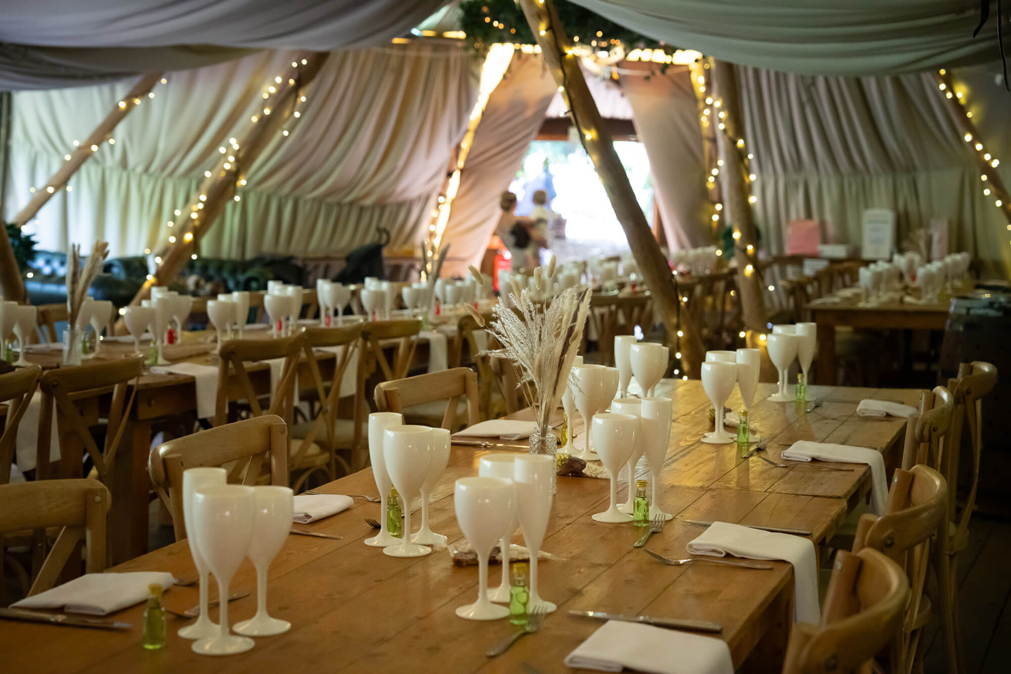 Rustic wedding reception tables inside the Hazlewood Castle woodland tipi.