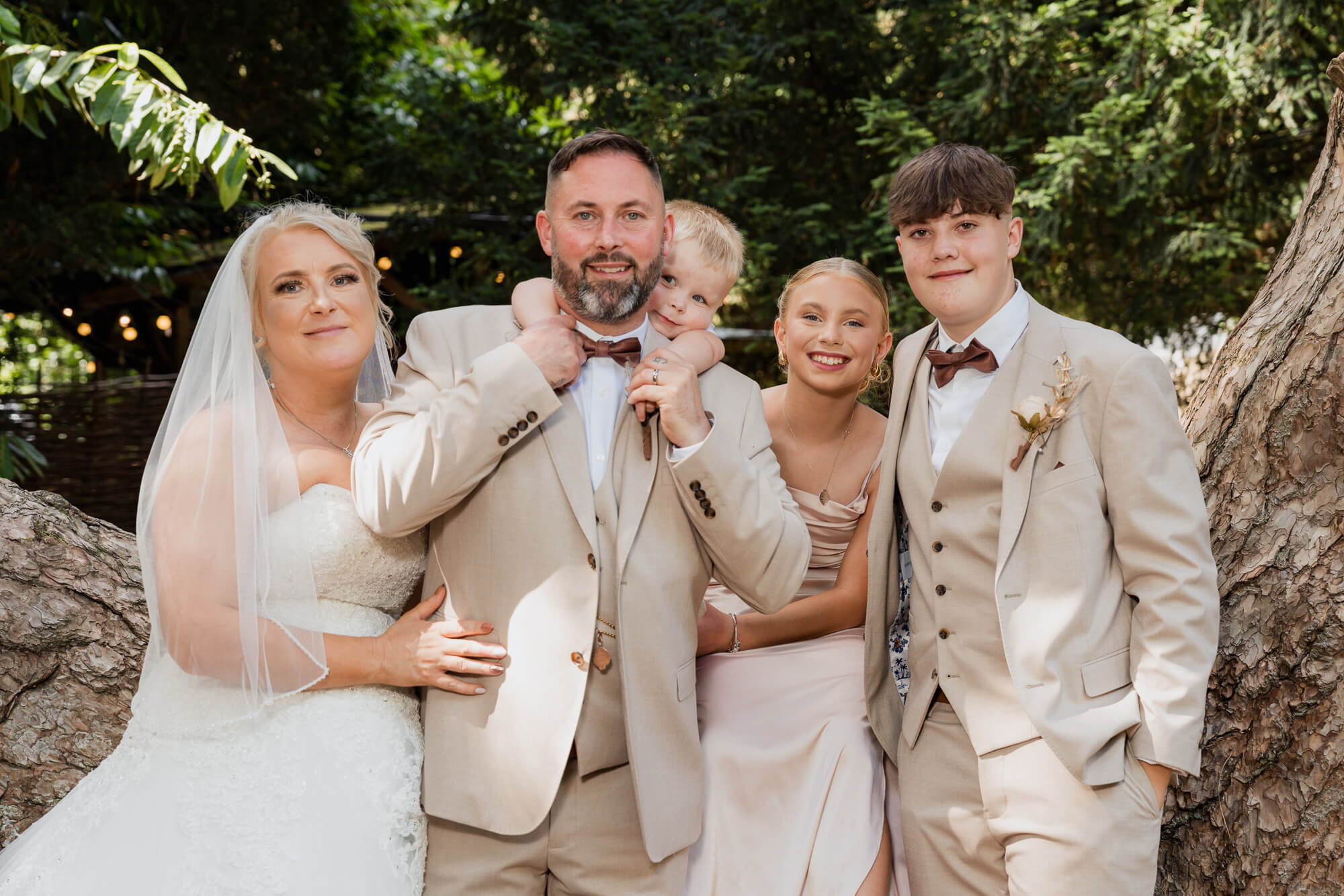 Newlyweds posing with their children after the Hazlewood Castle woodland wedding ceremony.