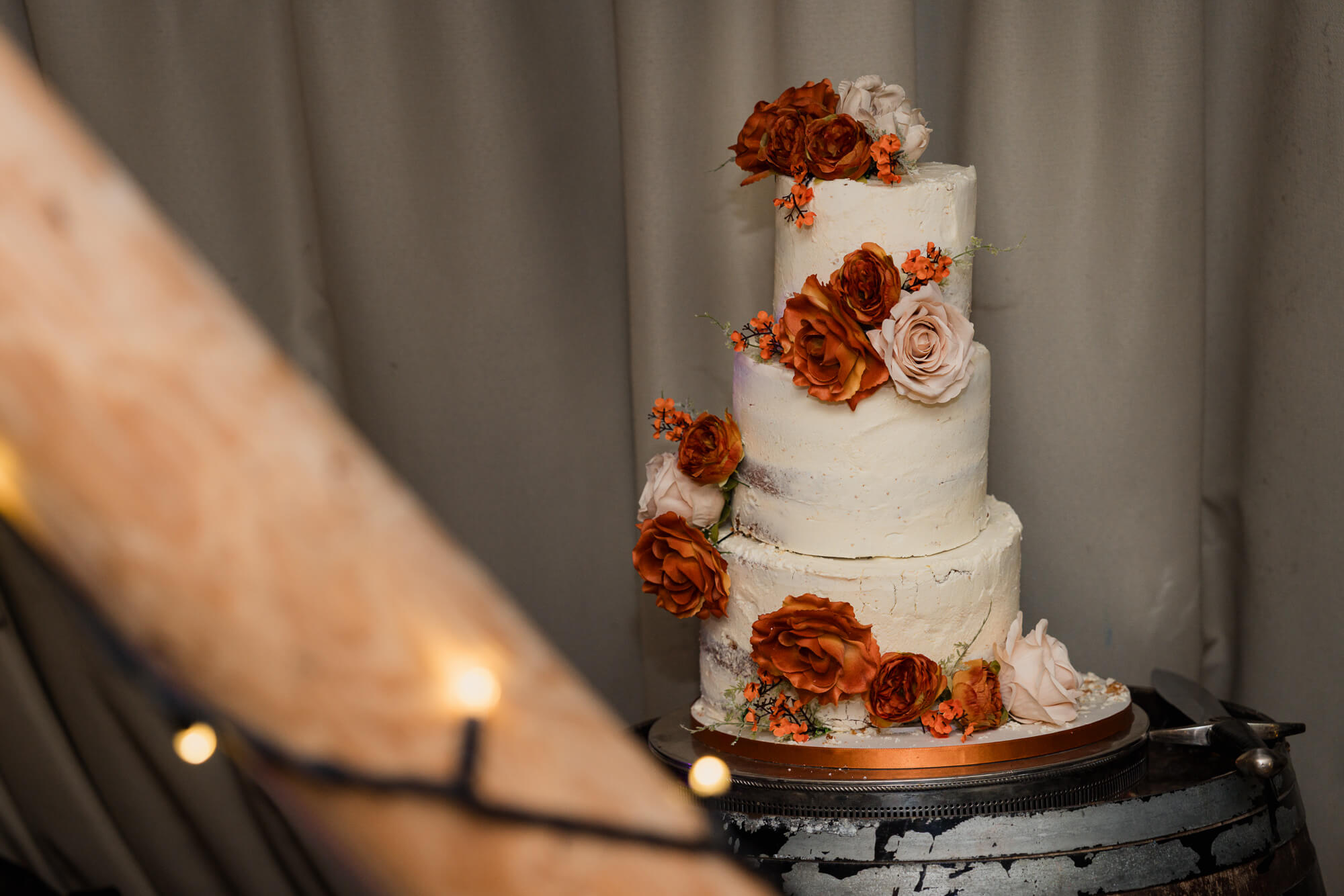 Rustic three-tier wedding cake with autumn flowers at Hazlewood Castle.