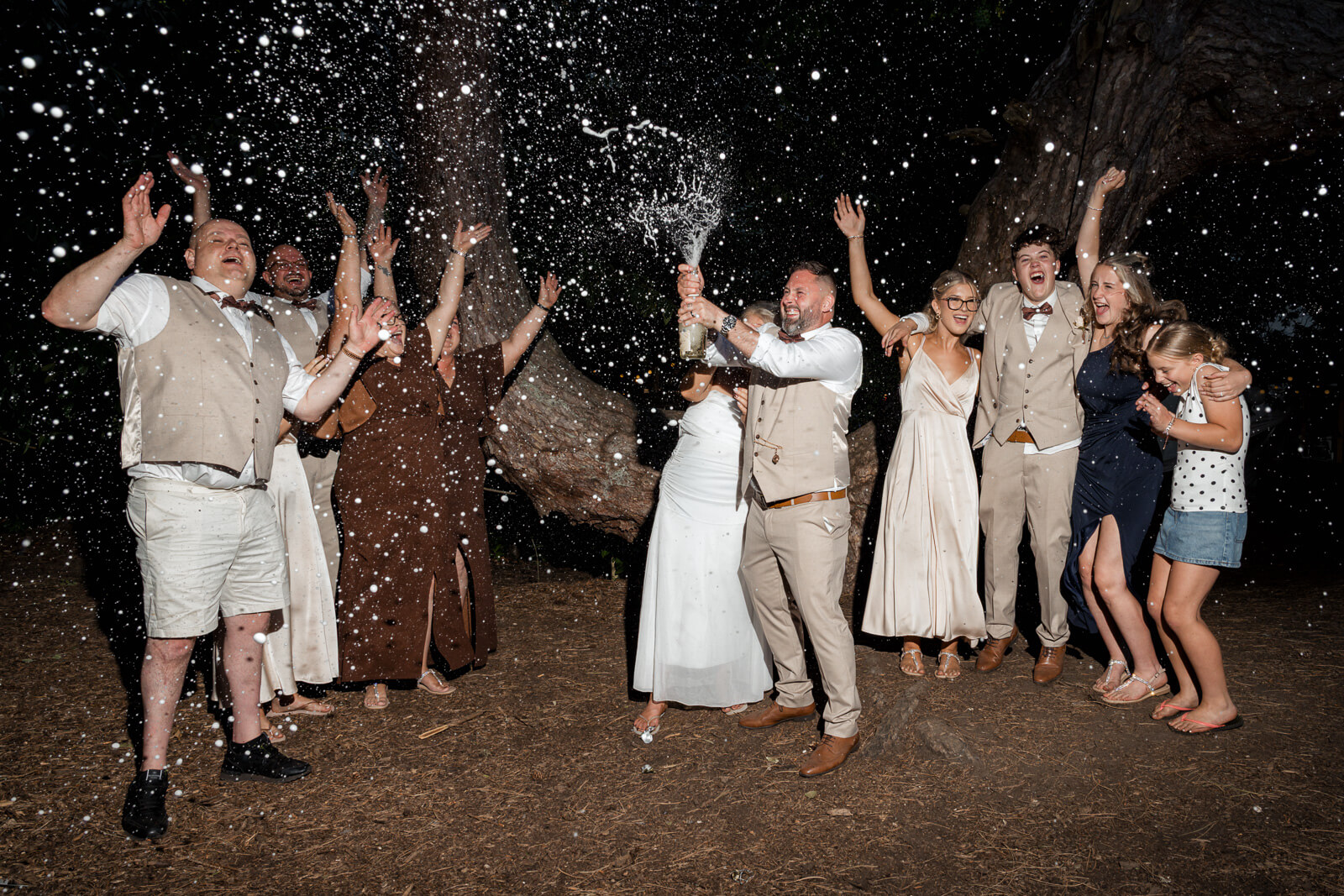 Champagne spray celebration during an evening woodland wedding at Hazlewood Castle.
