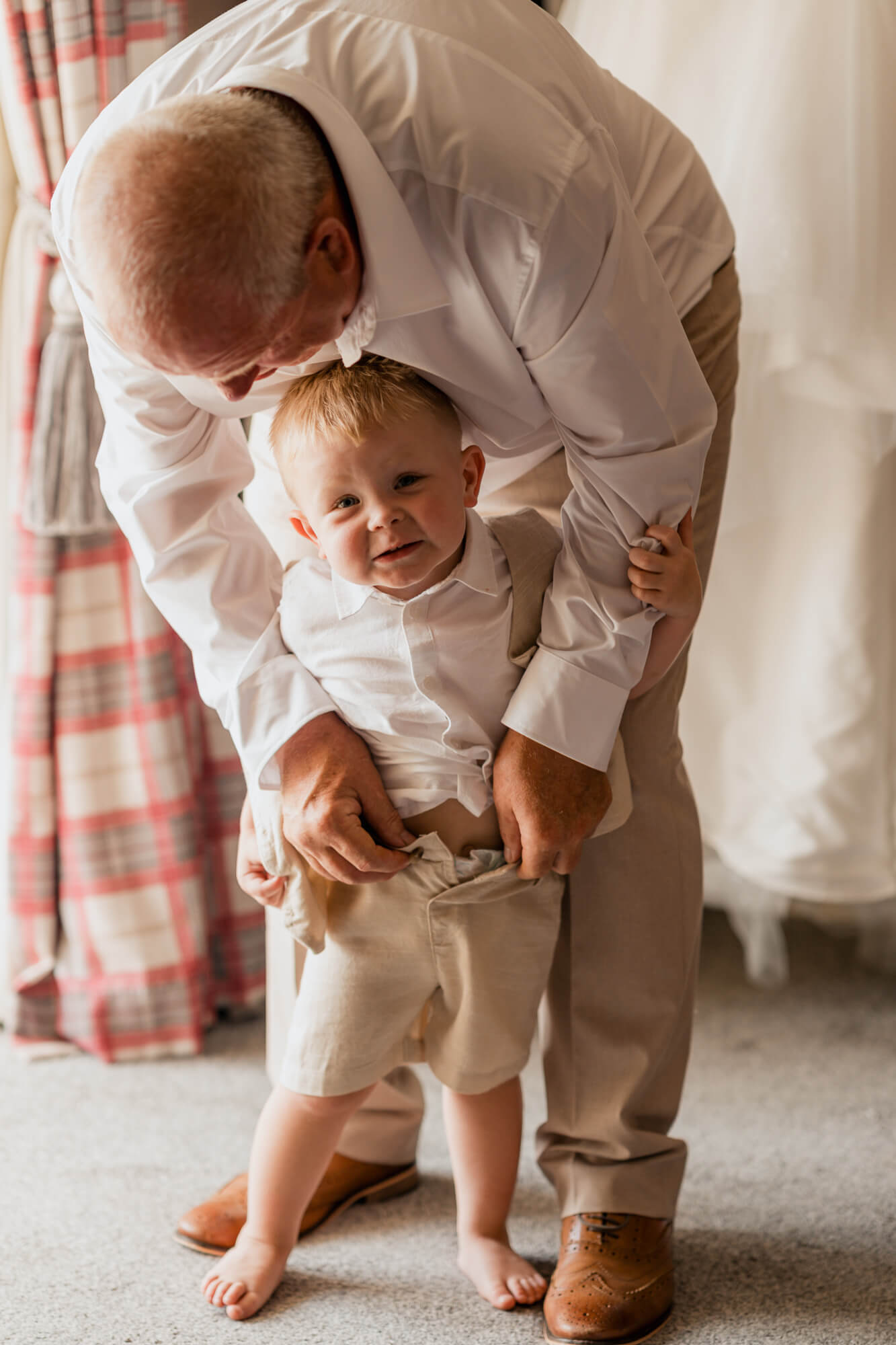 Grandfather helping a young page boy get ready for the wedding.