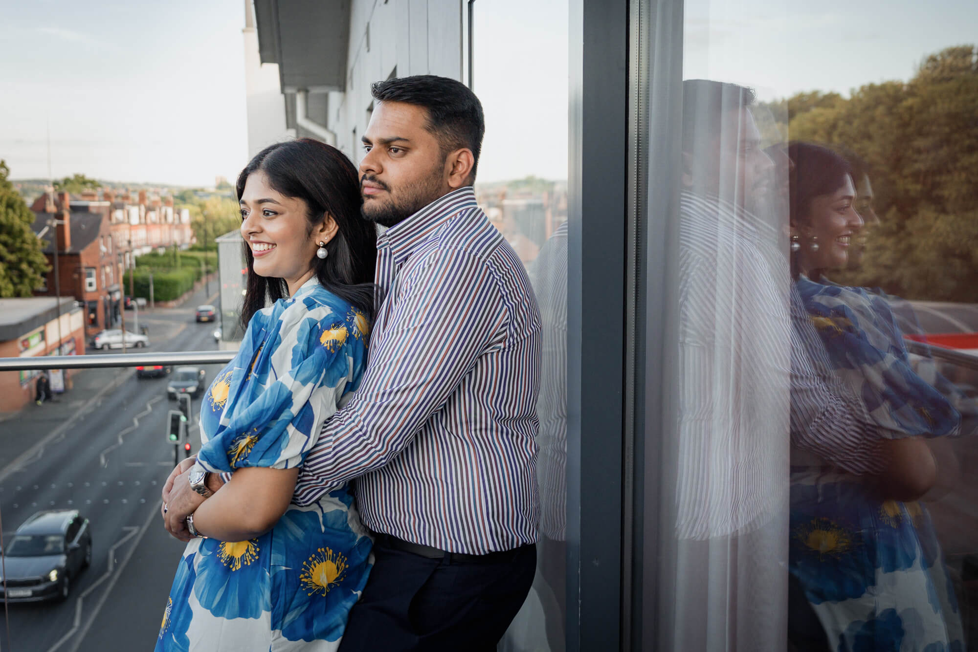 Couple embracing on a balcony with Leeds city views in the background.