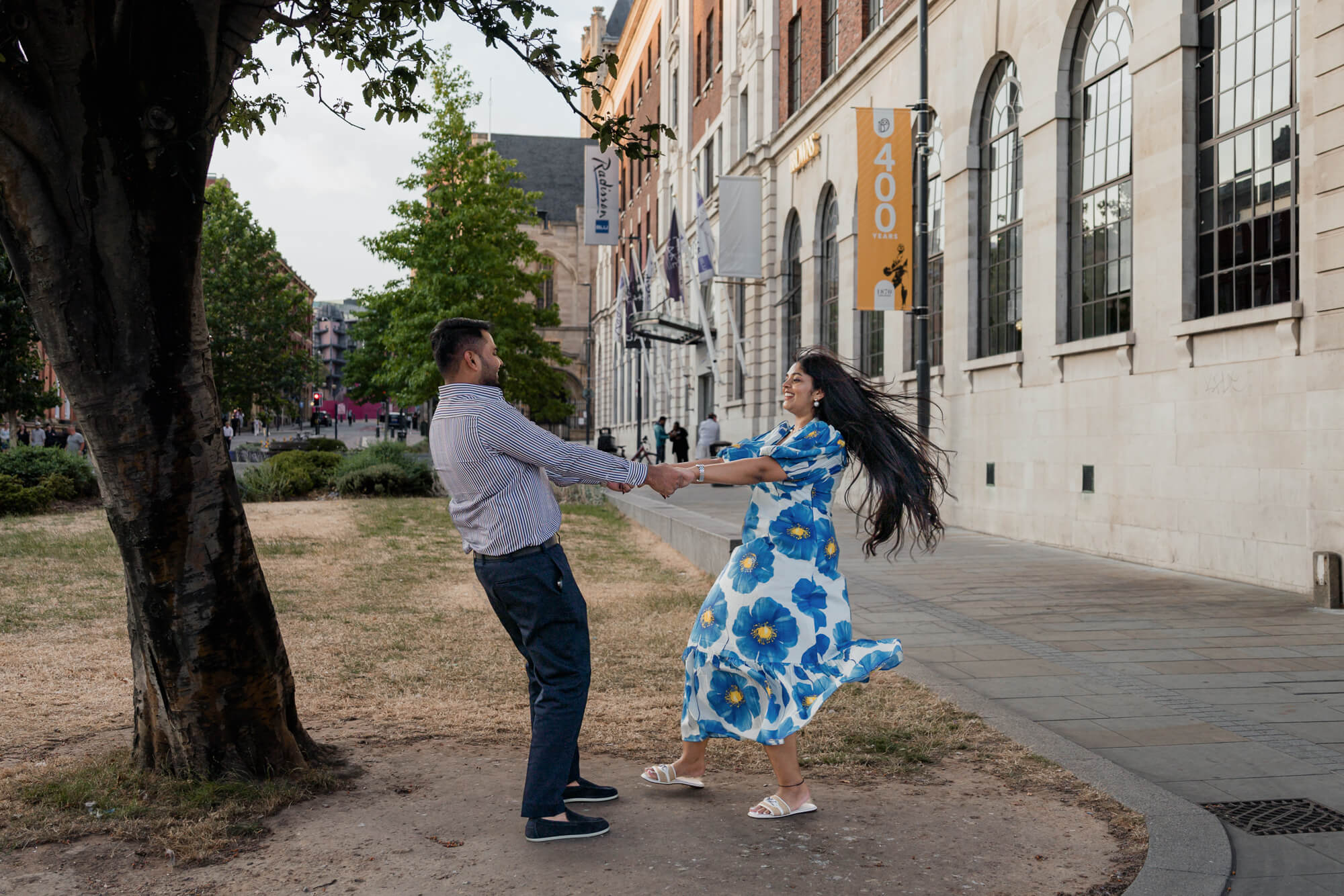 Couple spinning together beneath a tree during a romantic Leeds engagement photoshoot.