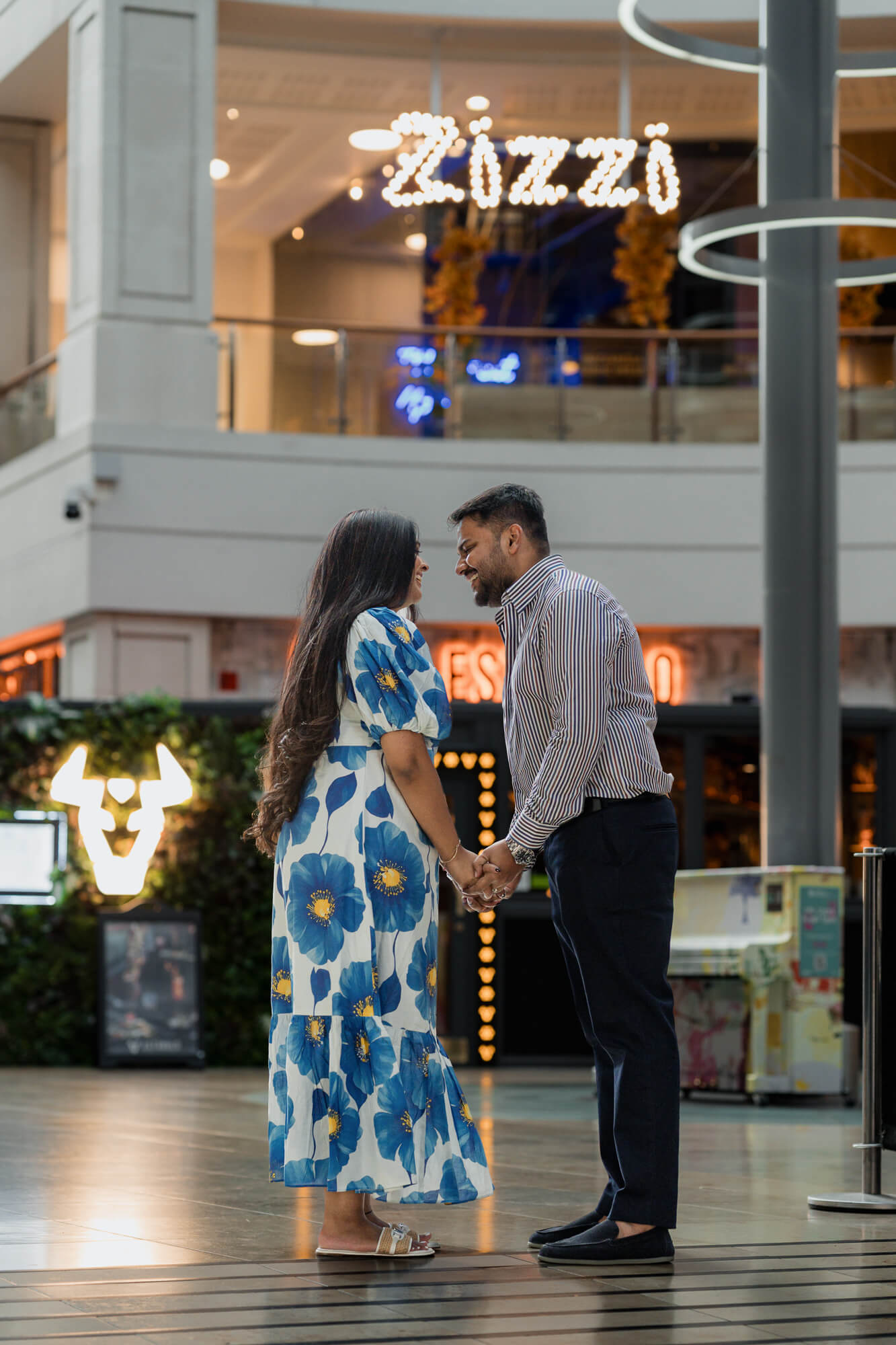 Couple holding hands beneath the Zizzi restaurant sign during a Leeds pre-wedding photoshoot.