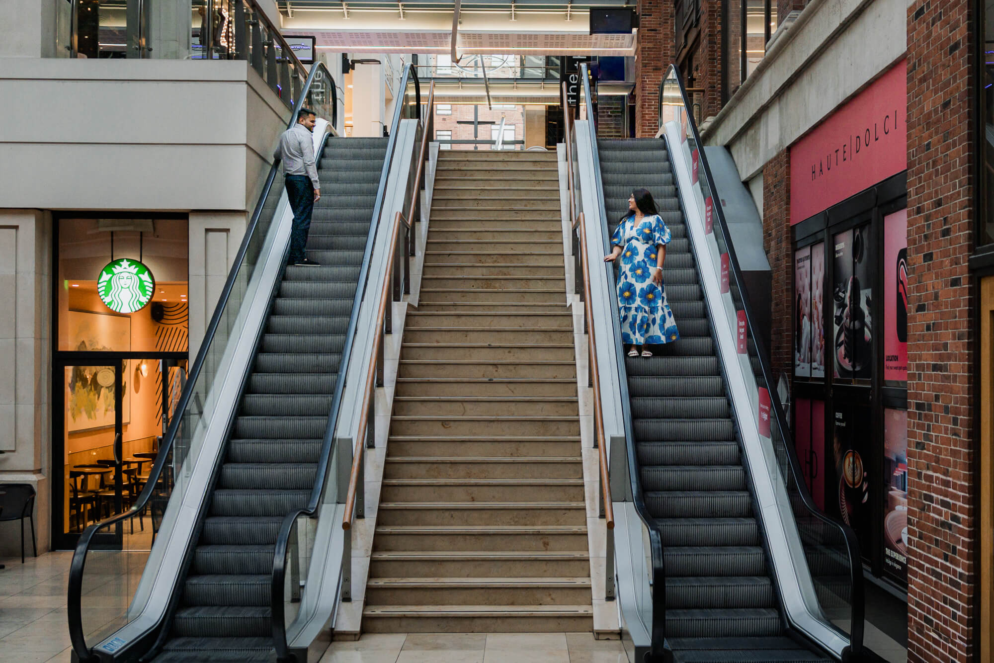 Creative engagement portrait with a couple riding opposite escalators in Leeds.