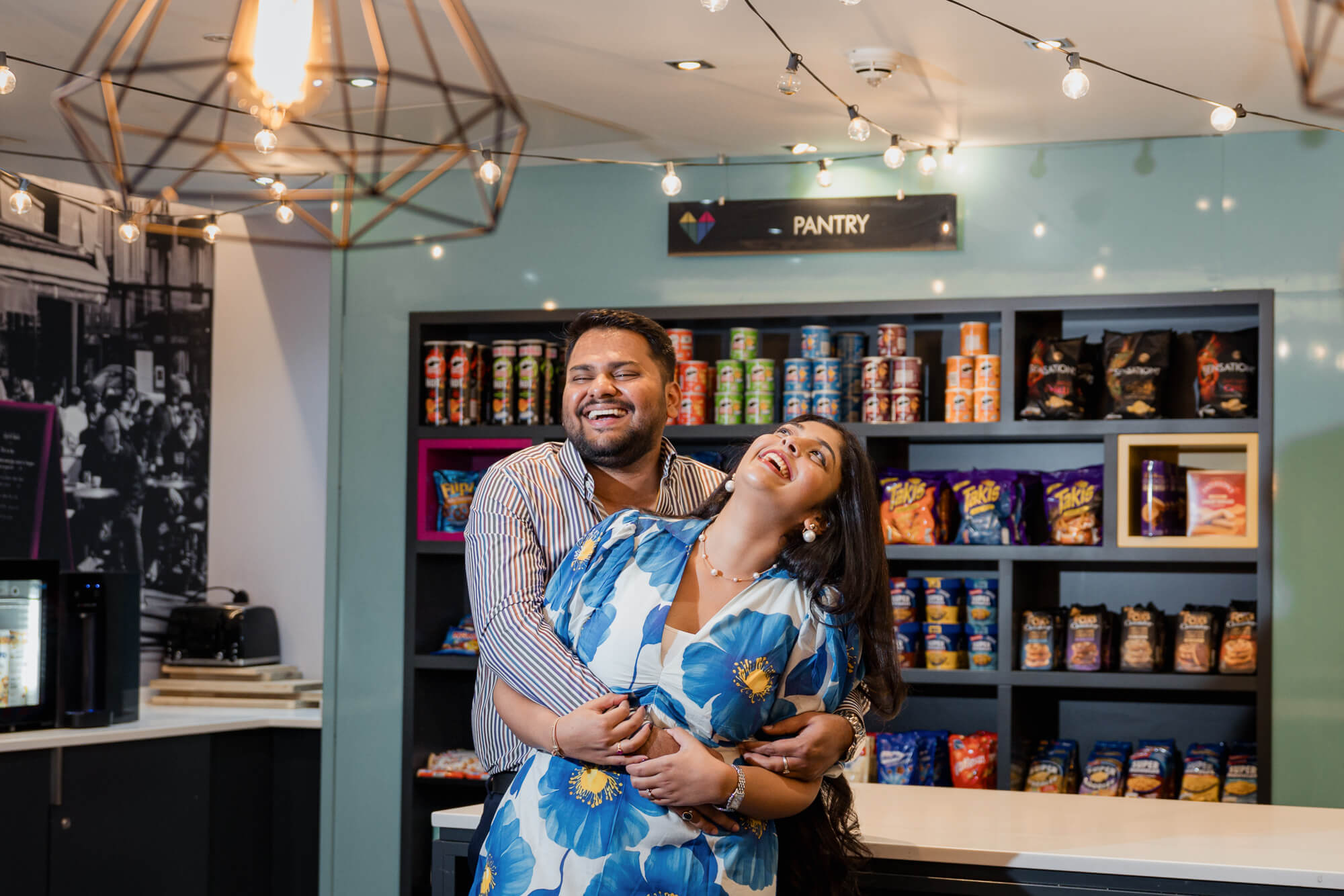 Couple laughing together inside the Iconinc Leeds pantry during their engagement session.