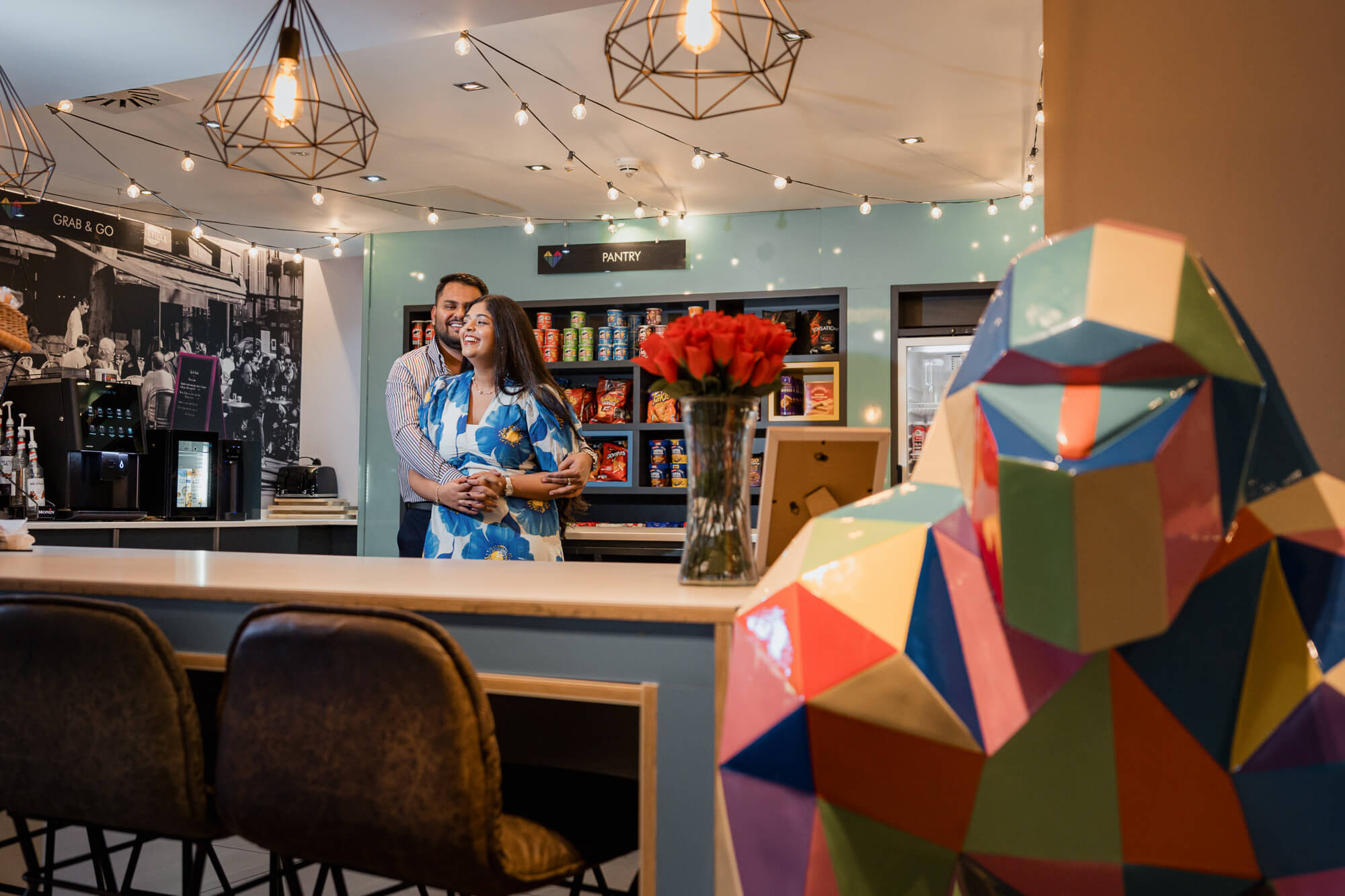 Romantic portrait of a couple inside Iconinc Leeds with colourful lion sculpture.