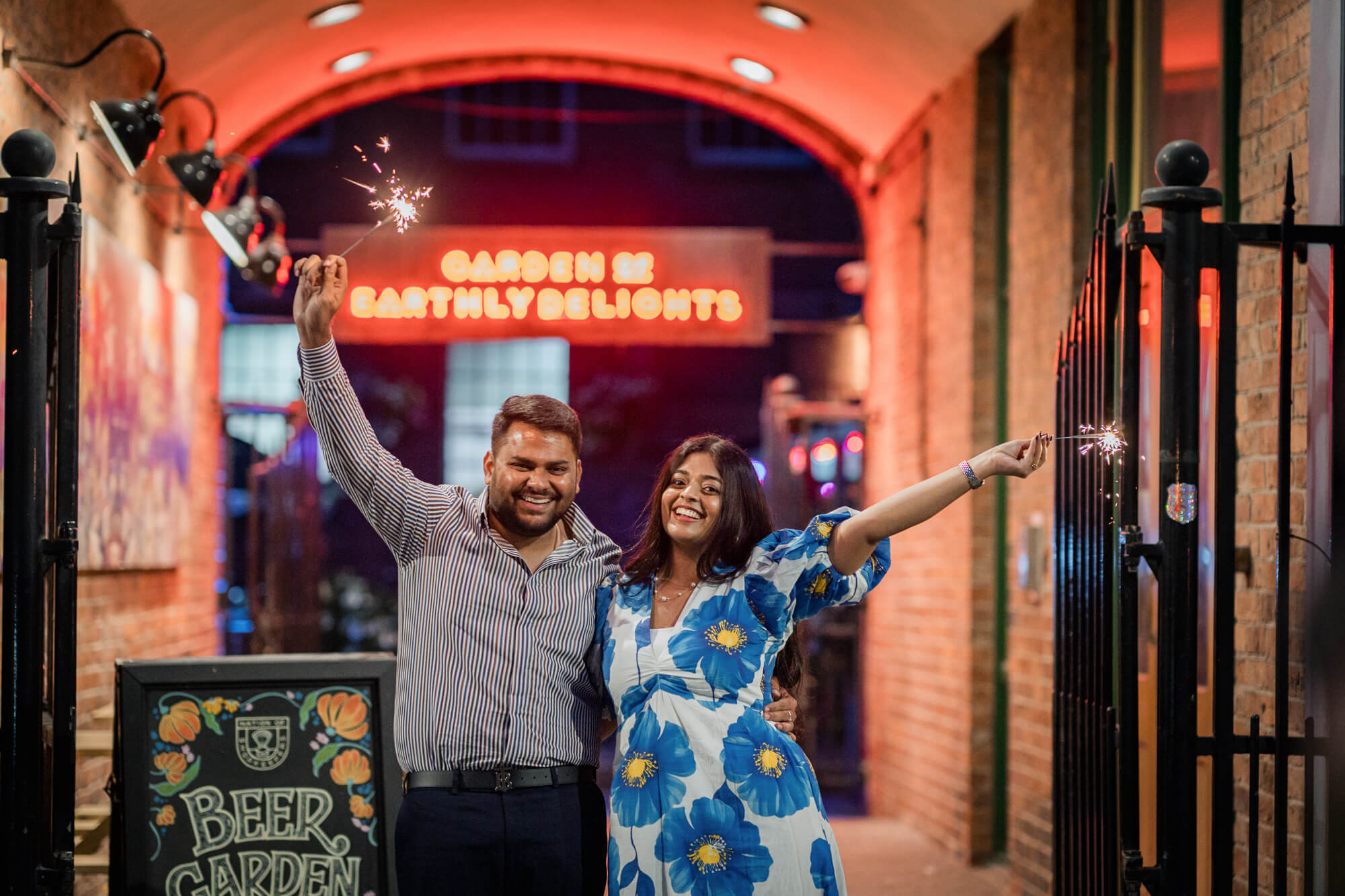 Couple holding sparklers beneath illuminated arches during an evening pre-wedding photoshoot in Leeds city centre.