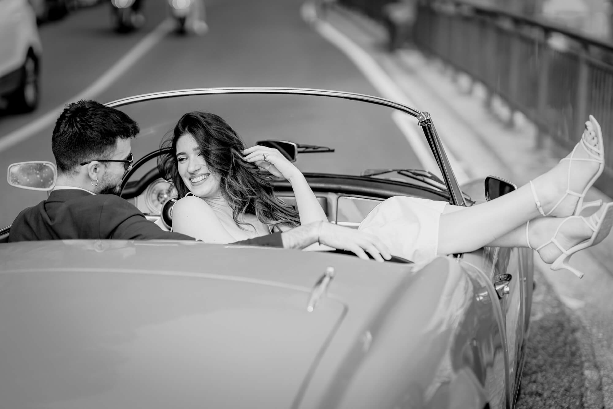 Timeless black and white wedding photograph of a couple in a classic car