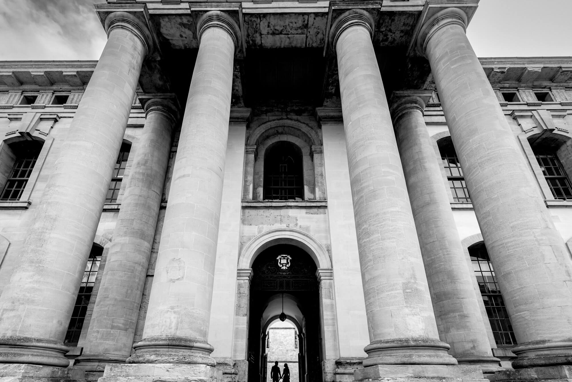 Black and white wedding photography of a couple beneath grand architectural columns
