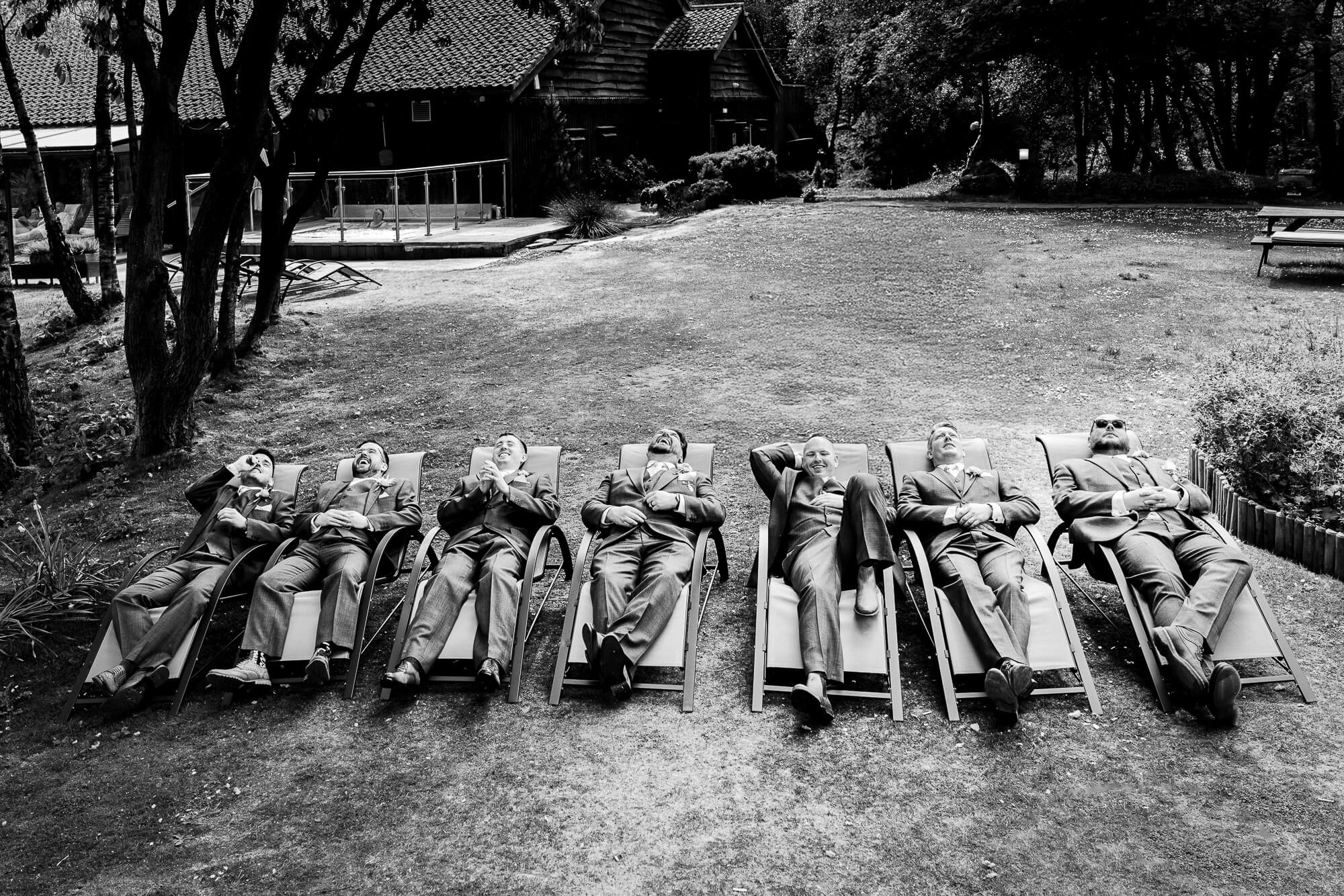 Fun black and white wedding photograph of groomsmen relaxing together