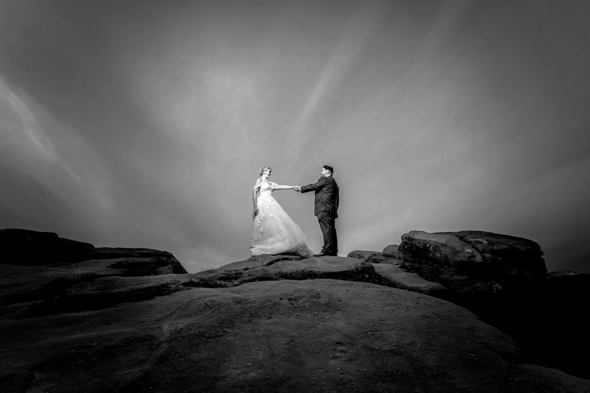 Creative black and white wedding photograph of a couple beneath a dramatic sky