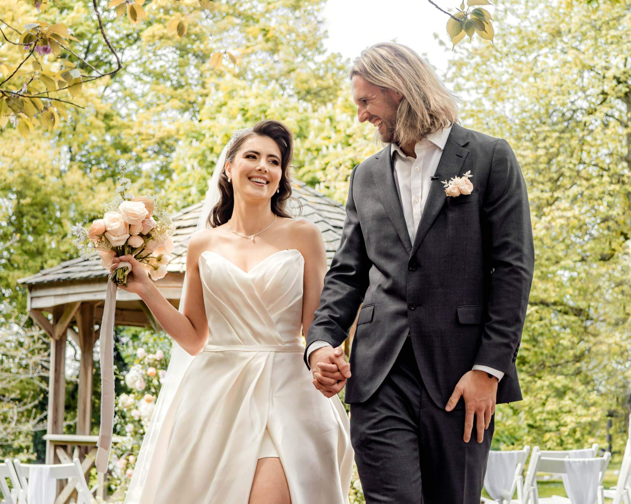 Bride and groom at Hazlewood Castle holding hands and smiling to each other right after religious ceremony.