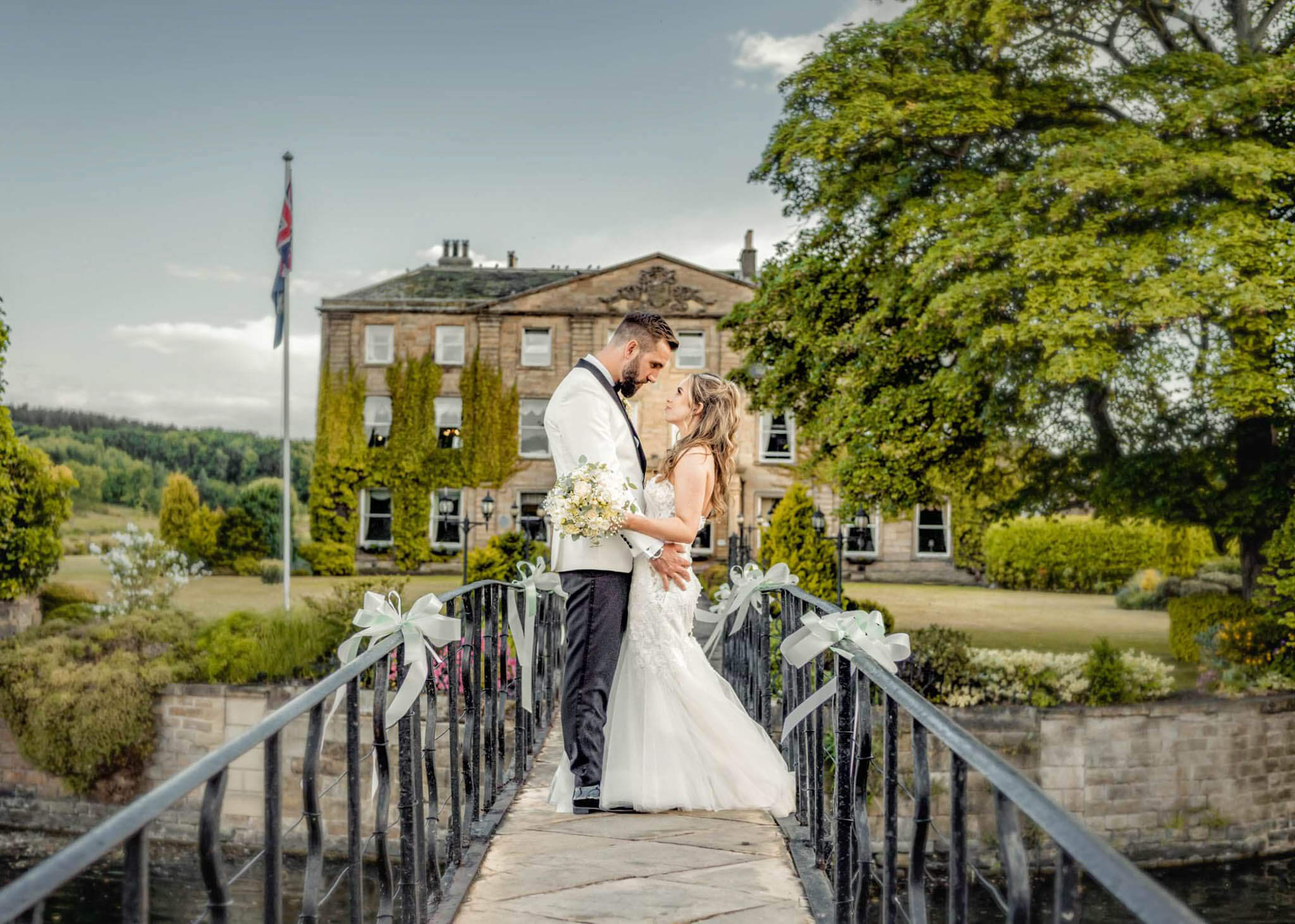 Groom and bride facing each other and holding arms, on the bridge of Waterton Park.