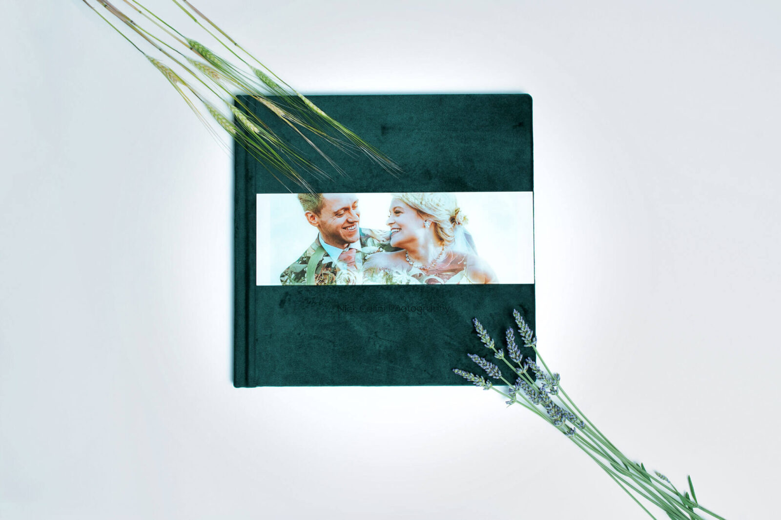 Showcasing a wedding album covered in green velvet with an acrylic picture on the cover.