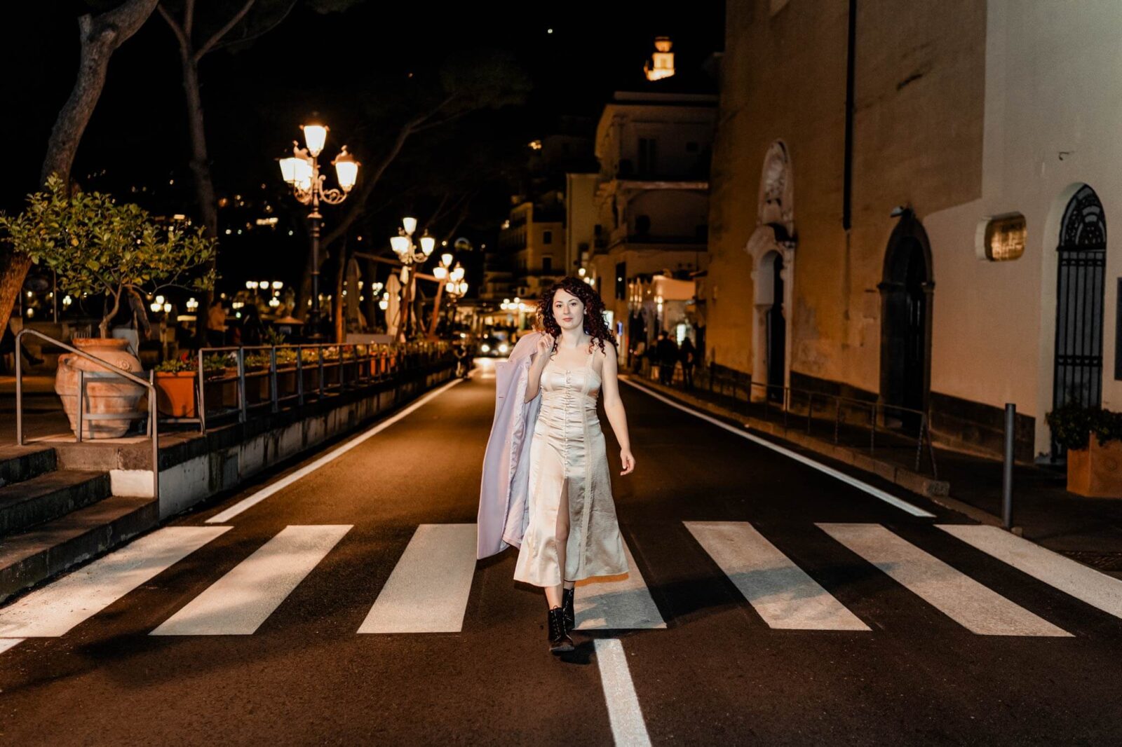 Girl walking in the middle of the road, night time, lighten by road lights.